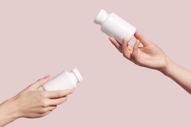Ręce trzymające puste białe plastikowe rurki na różowym tle Makieta marki produktu Medic
