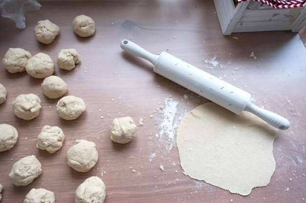 Zdjęcie ręce ugniatają grube ciasto wałkiem na stole kuchennym ozdobionym świątecznymi dekoracjami na boże narodzenie i nowy rok pieczenie w domu aromat i wygoda