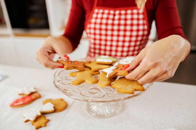 Ręce układające świąteczne ciasteczka imbirowe na talerzu