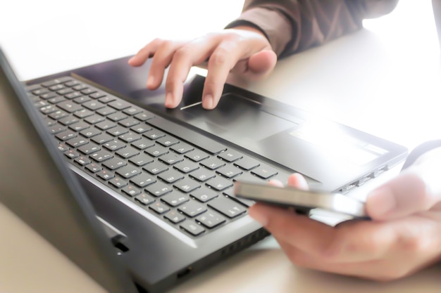 Ręce używające laptopa i smartfona do zakupów internetowych z miękkim światłem dziennym o wysokim kontraste
