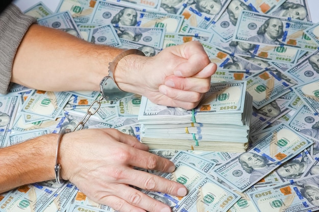 Zdjęcie ręce w kajdankach niebezpieczeństwo biznesowe związane z nieruchomościami z dolarami w koncepcji pondemicznej