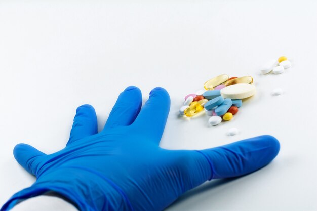 Zdjęcie ręce w medycznych niebieskich rękawiczkach trzymają garść kolorowych tabletek