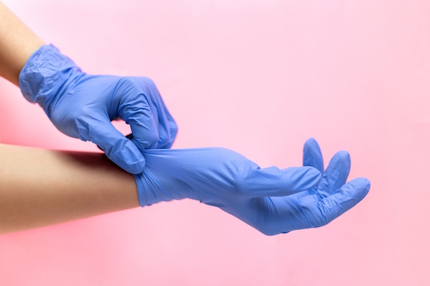 Ręce w rękawiczkach medycznych na różowym tle Proces zakładania rękawiczek