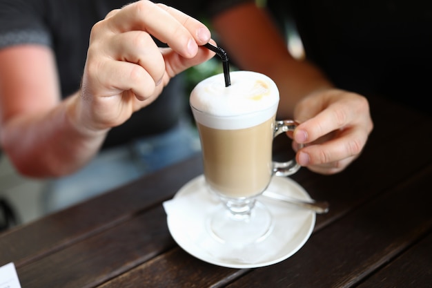 Ręce wkładając słomkę do szklanki latte
