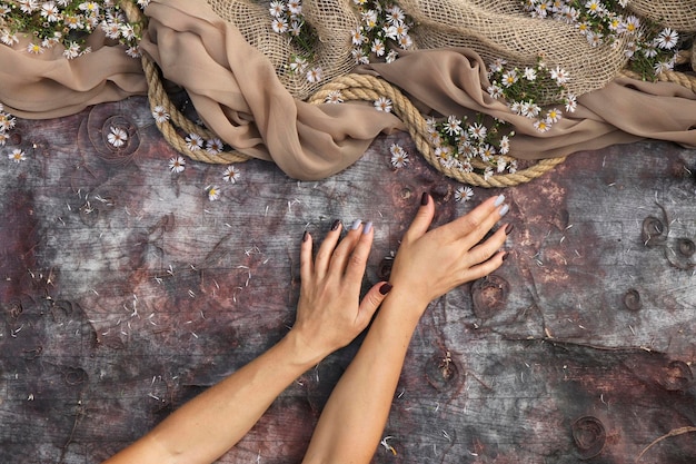 Ręce z brązowym i niebieskim manicure na tle vintage z kwiatami.