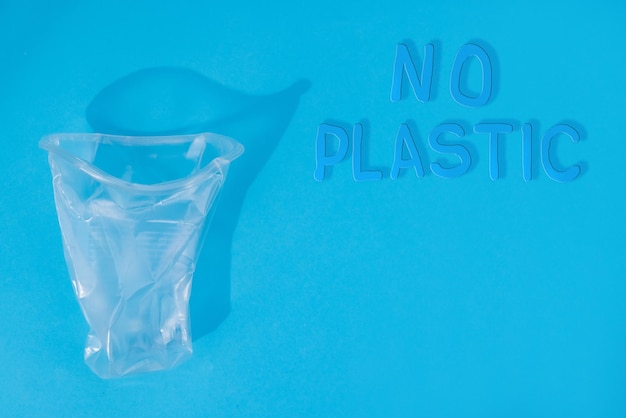 Zdjęcie ręce zgniatają plastikowy kubek na niebieskim tle koncepcja ekologii bez plastiku