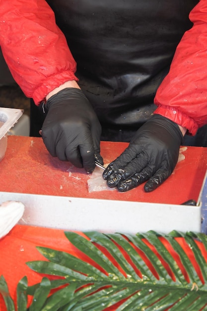 Ręczne cięcie łososia na czerwonej tablicy w geście zbliżenia