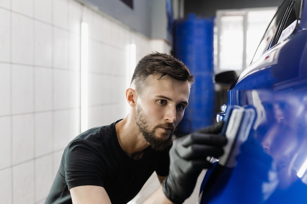 Ręczne nakładanie nanoceramicznej powłoki ochronnej w celu ochrony samochodu przed zarysowaniami Proces nakładania warstwy ceramicznej na karoserię za pomocą gąbki w serwisie detailingowym