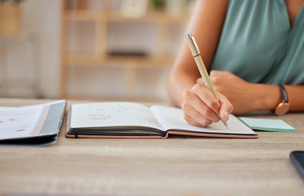 Ręczne pióro i pisanie w notatniku z kobietą biznesową siedzącą przy biurku w swoim biurze do planowania harmonogramu porządku dziennego i spotkania z pracownicą robiącą notatkę w swoim dzienniku lub pamiętniku