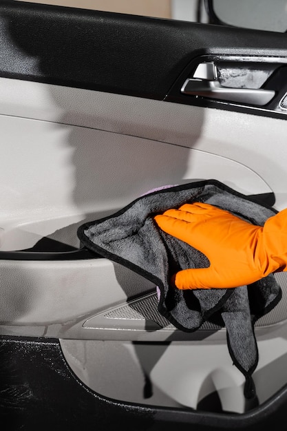 Ręczne suszenie wnętrza samochodu panelu karty drzwi samochodu za pomocą mikrofibry w szczegółowym serwisie samochodowym Pracownik czyszczący suche wnętrze samochodu