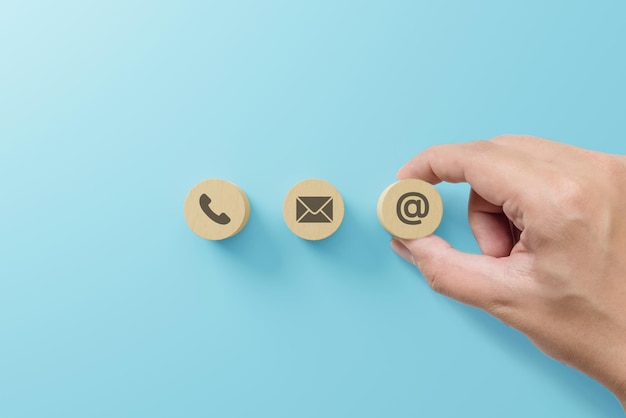 Ręczne wkładanie drewnianego klocka z symbolem telefonu adres e-mail Strona internetowa skontaktuj się z nami lub koncepcja marketingu e-mailowego