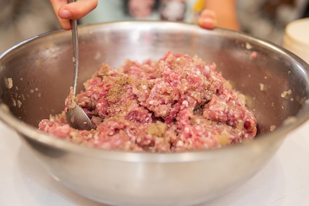 ręcznie mieszając mięso mielone w metalowej misce po dodaniu pieprzu