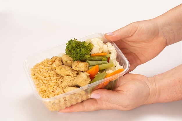 Ręcznie podawany zdrowy kurczak w pudełku na lunch z widokiem z góry na czystym białym tle