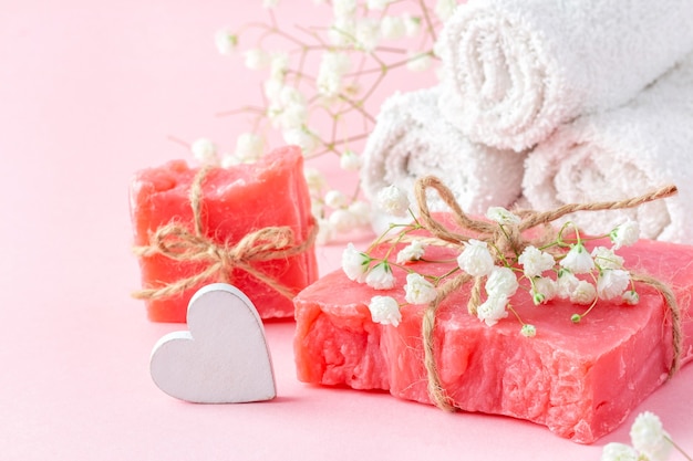 Ręcznie robiona kostka mydła i białe ręczniki ozdobione łyszczecą na różowo