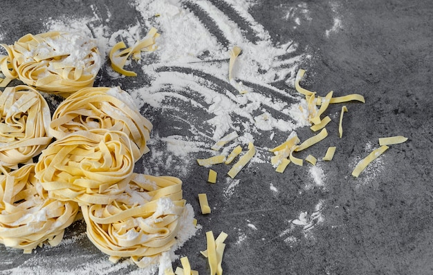 Ręcznie robiony makaron surowego Tagliatelle z mąką na ciemnym stole