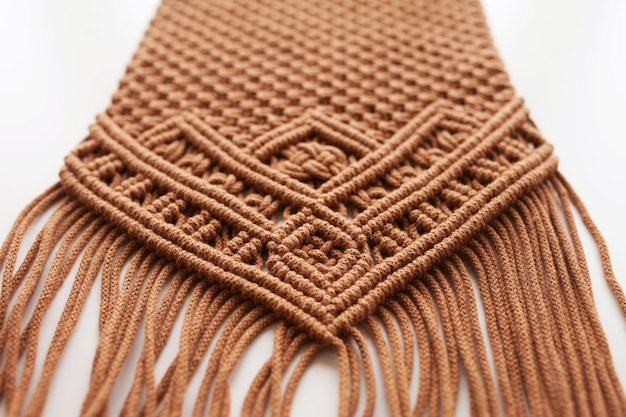 Ręcznie robiony wzór makramy z bliska. Macrame oplot i nici bawełniane na drewnianym stole. Kobiece hobby. Przyjazna dla środowiska nowoczesna dziewiarska koncepcja naturalnej dekoracji DIY we wnętrzu. Skopiuj miejsce