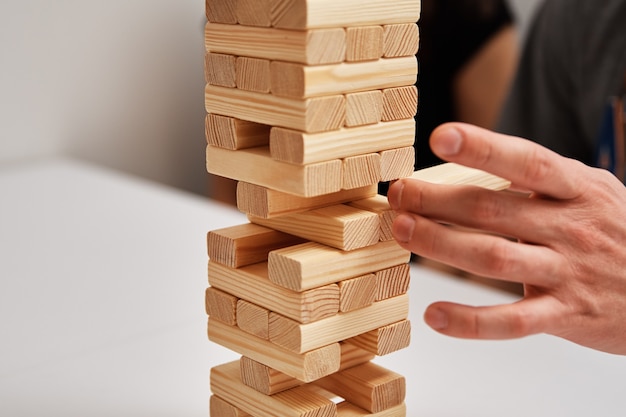 Ręcznie weź jeden blok z drewnianej wieży na białym tle gra planszowa rozrywki rodzinnej