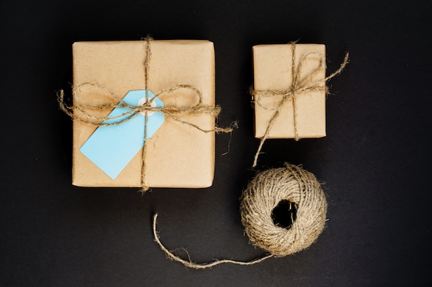 Ręcznie wykonane pudełka na prezenty owinięte papierem rzemieślniczym z niebieską kartką z papieru i sznurkiem do dekoracji.