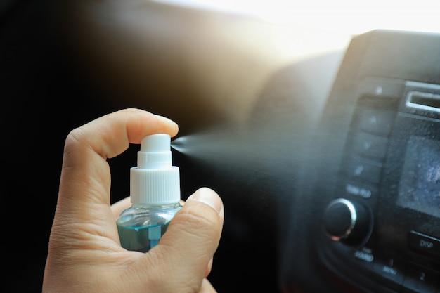 ręcznie za pomocą sprayu alkoholowego do czyszczenia kontrolerów mediów z wirusa Corona lub bakterii w samochodzie codziennego użytku. zapobiec koncepcji Covid 19