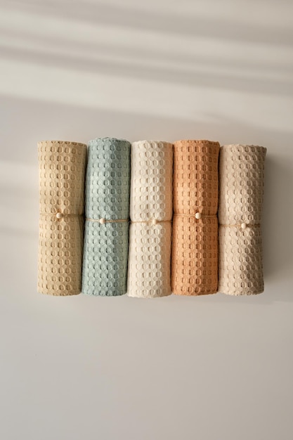 Zdjęcie ręczniki domowe z naturalnego muślinu w pastelowych odcieniach ułożone starannie w rzędzie i ozdobione sznurkiem z koralikiem naturalne, miękkie i stylowe tekstylia domowe