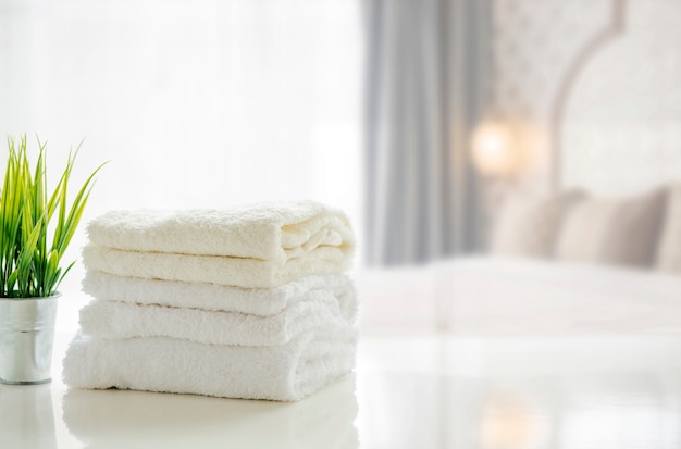 Ręczniki na białym stole z kopii przestrzenią na zamazanym sypialni tle