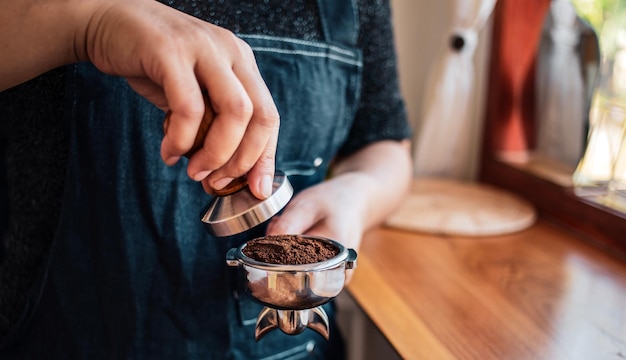 Zdjęcie ręczny barista lub ekspres do kawy trzymający portafilter i ubijak do kawy robiący kawę espresso