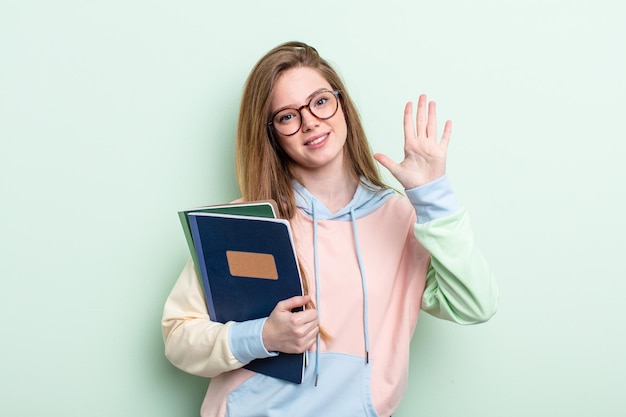 Redhair kobieta uśmiecha się i wygląda przyjaźnie, pokazując numer pięć. koncepcja studenta