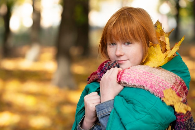 Redhaired dziewczyna z liśćmi klonu w jesiennym parku Dzieci jesienią