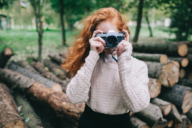 Zdjęcie redhead dziewczyna trzyma aparat fotograficzny w parku jesienią