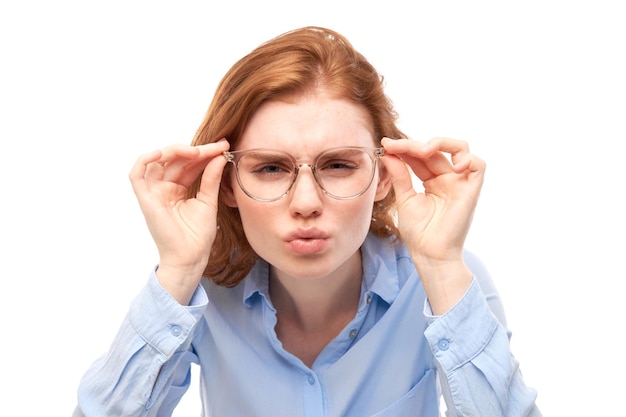 Redhead młoda kobieta ma na sobie okulary mrużąc oczy patrząc na kamery na białym tle Problemy z wizją koncepcji