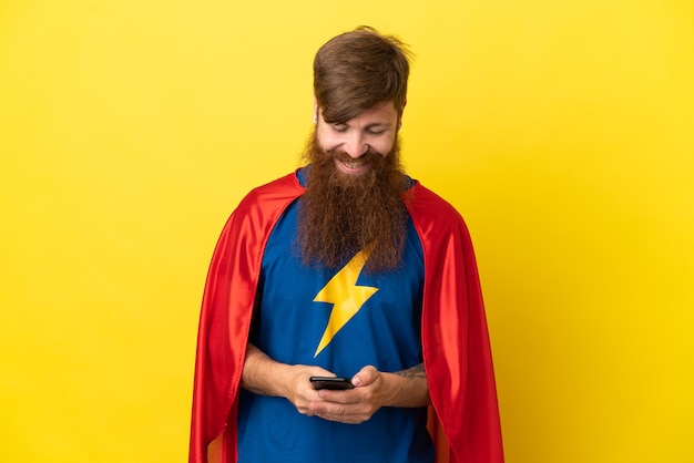 Redhead Super Hero mężczyzna na białym tle na żółtym tle wysyłanie wiadomości za pomocą telefonu komórkowego