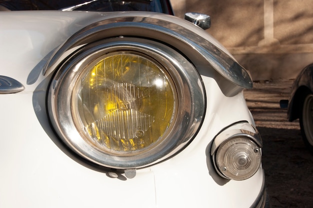 Reflektor starego białego samochodu w zbliżeniu