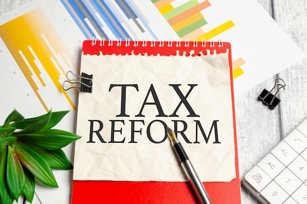 Reforma podatkowa WORD na papierze i czerwony notatnik na drewnianym tle