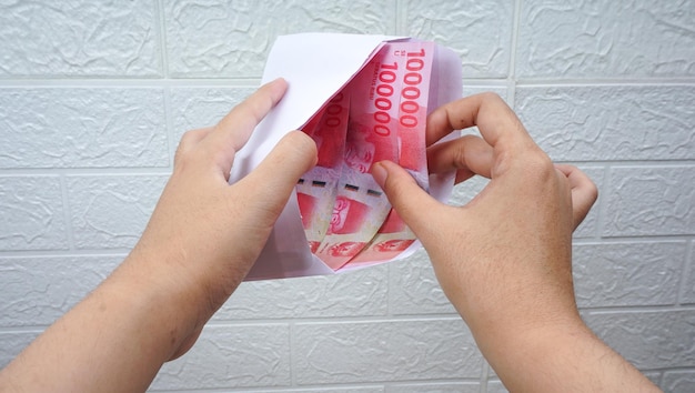 Ręka biorąca lub wkładająca pieniądze do koperty rupia waluty indonezyjskiej