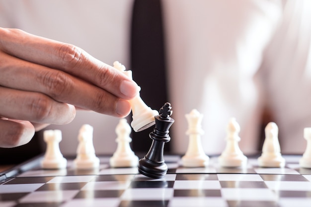 Ręka biznesmena use królewiątko szachowego kawałka biała bawić się gra trzaskać obalenie