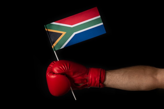 Ręka Boksera Trzyma Flagę Republiki Południowej Afryki. Rękawica Bokserska Z Flagą Republiki Południowej Afryki. Czarne Tło.