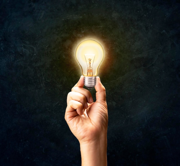 Ręka dotykająca elektryczna lampa wolframowa żarówka w ciemności Biznesowa ręka trzyma żarówkę koncepcja nowych pomysłów innowacja inspiracja kreatywne myślenie rozwiąż problem Business Finance Solutions