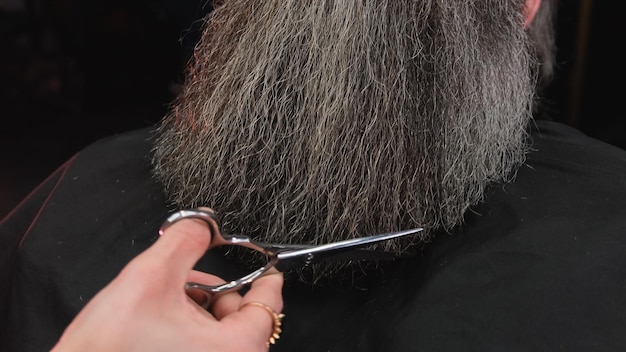 Ręka fryzjera przeczesuje brodę mężczyzny grzebieniem