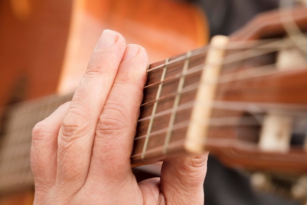 Ręka gitarzysty lub ręka muzyka w akordzie F-dur na strunie gitary akustycznej w miękkim naturalnym kolorze