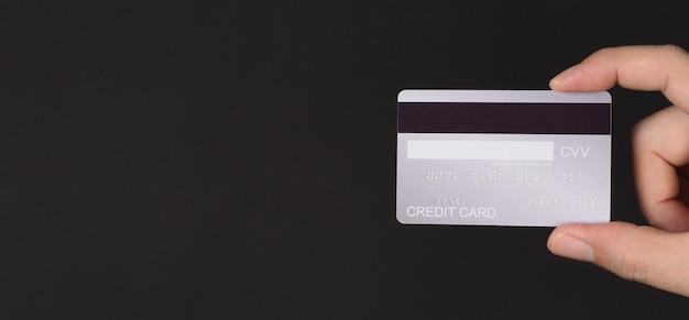 Ręka jest pokazana z tyłu srebrnej karty kredytowej na białym tle