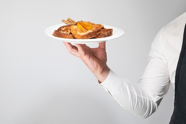 Ręka kelnera podnosząca talerz wykwintnych torrijas Hiszpański słodycz spożywana podczas Wielkanocy