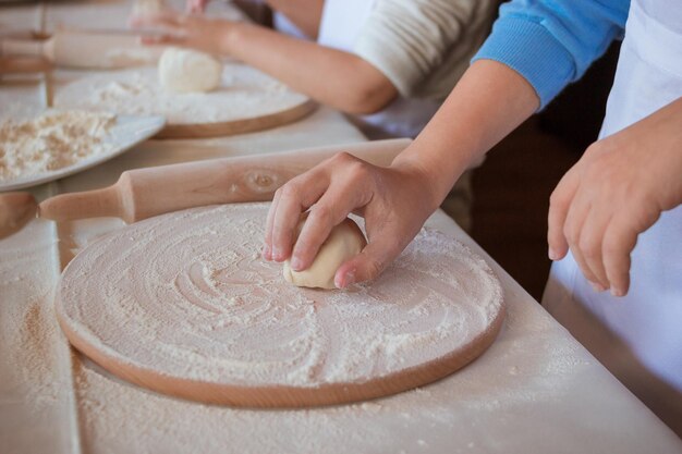 Ręka kładzie ciasto drożdżowe na drewnianej desce do krojenia posypanej mąką