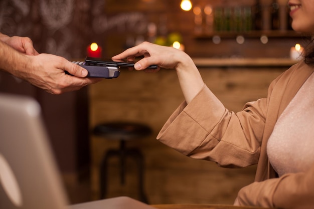 Zdjęcie ręka klienta płaci za pomocą bezstykowej technologii telefonii komórkowej w kawiarni. kobieta płaci telefonem komórkowym za kawę. działalność handlowa w kawiarni.