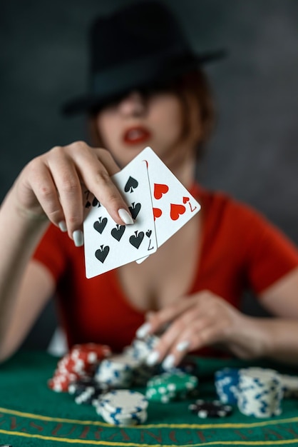 Ręka kobiety bierze karty do pokera na okrągłym zielonym stole do pokera ryzykowne zakłady w pokera kobieta w kasynie do pokera