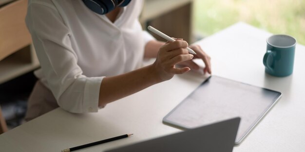 Ręka kobiety biznesu z bliska za pomocą rysika pracuje na tablecie cyfrowym w miejscu pracy