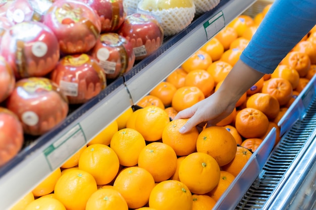 Ręka kobiety kupowanie pomarańczy w supermarkecie