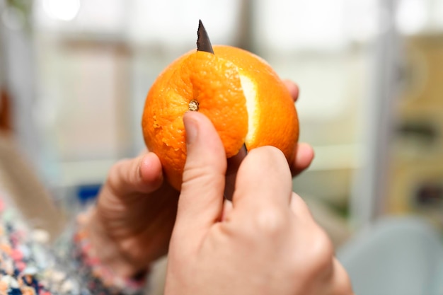 Zdjęcie ręka kobiety obiera pomarańczę