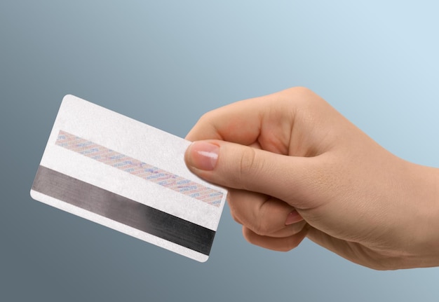 Ręka kobiety pokazująca kartę kredytową na szarym tle