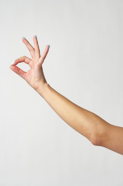 Ręka kobiety pokazująca znak ok na białym tle