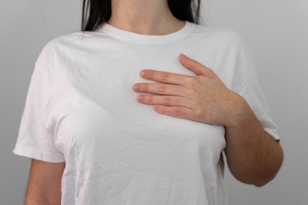 Ręka kobiety sprawdza guzki na piersi pod kątem oznak raka piersi na szarym tle